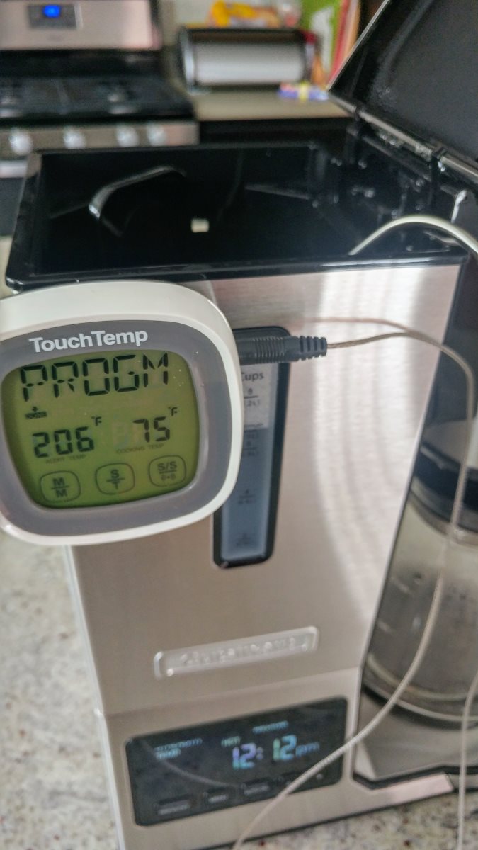 A digital thermometer is attached to the side of a Cuisinart coffeemaker. It shows the water temperature in the reservoir is at 75 degrees Fahrenheit.